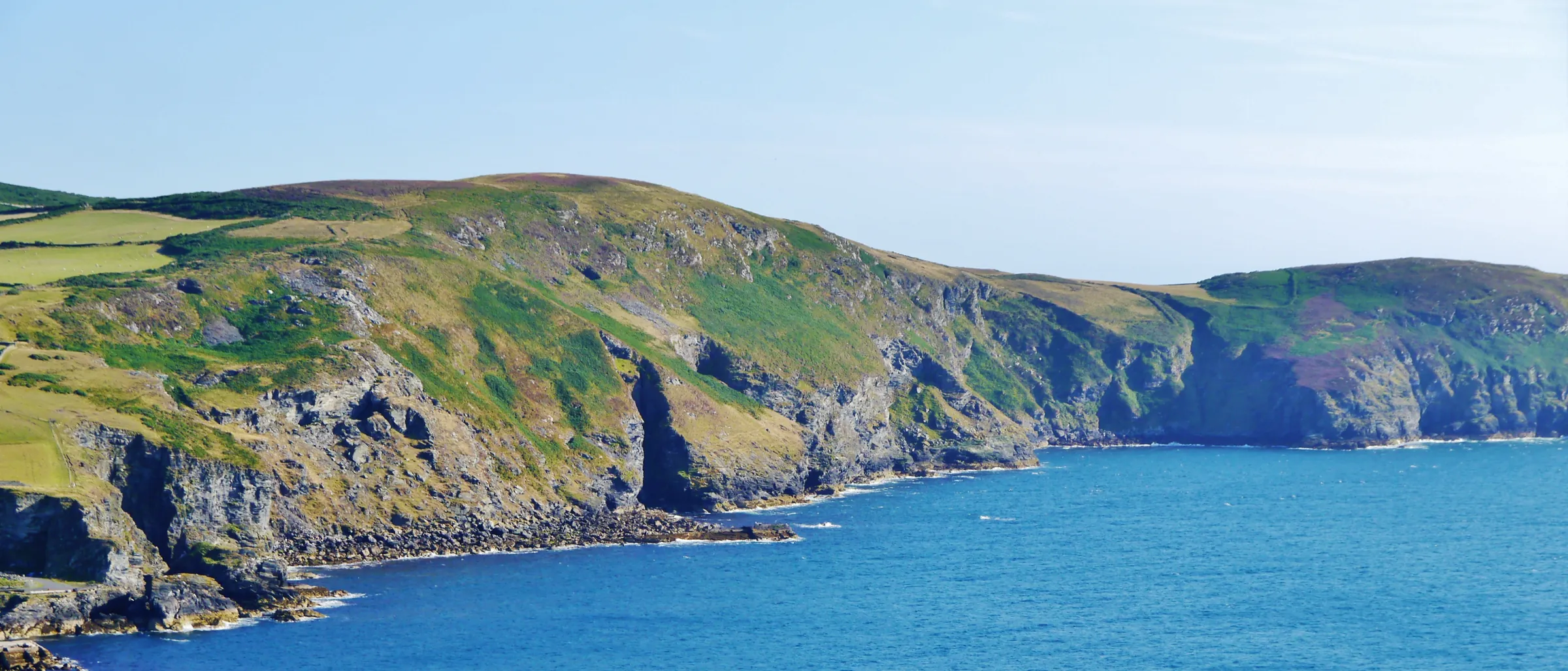The south-west coast of the Isle of Man from Bradda Head — green cliffs dropping into turquoise sea
